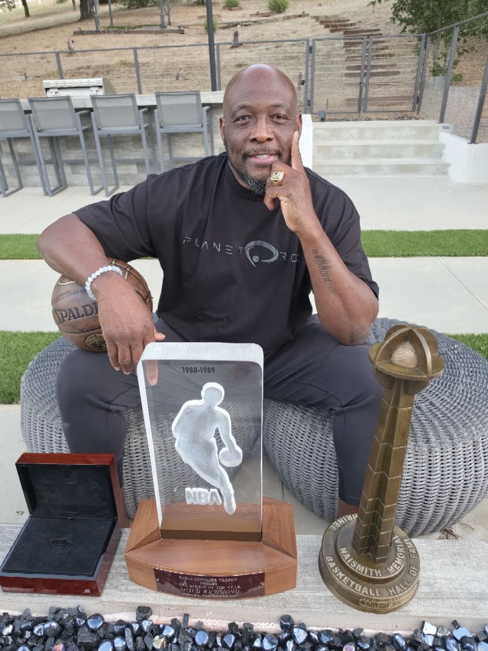 Mitch Richmond seated with his Rookie of the Year trophy, Hall of Fame trophy and Hall of Fame ring